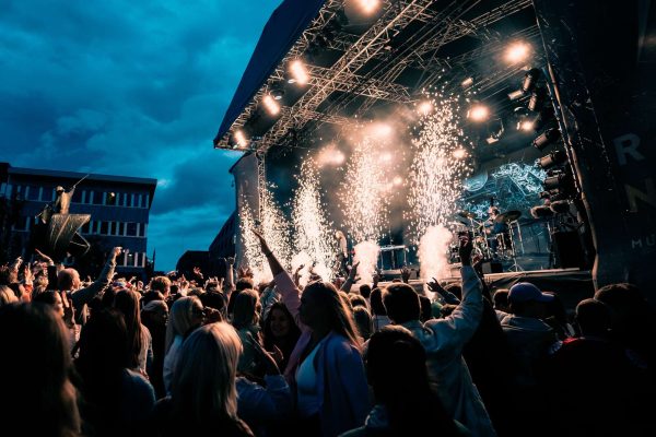 a large crowd at a concert on a bright day with firework a large crowd at a concert on a bright day with firework